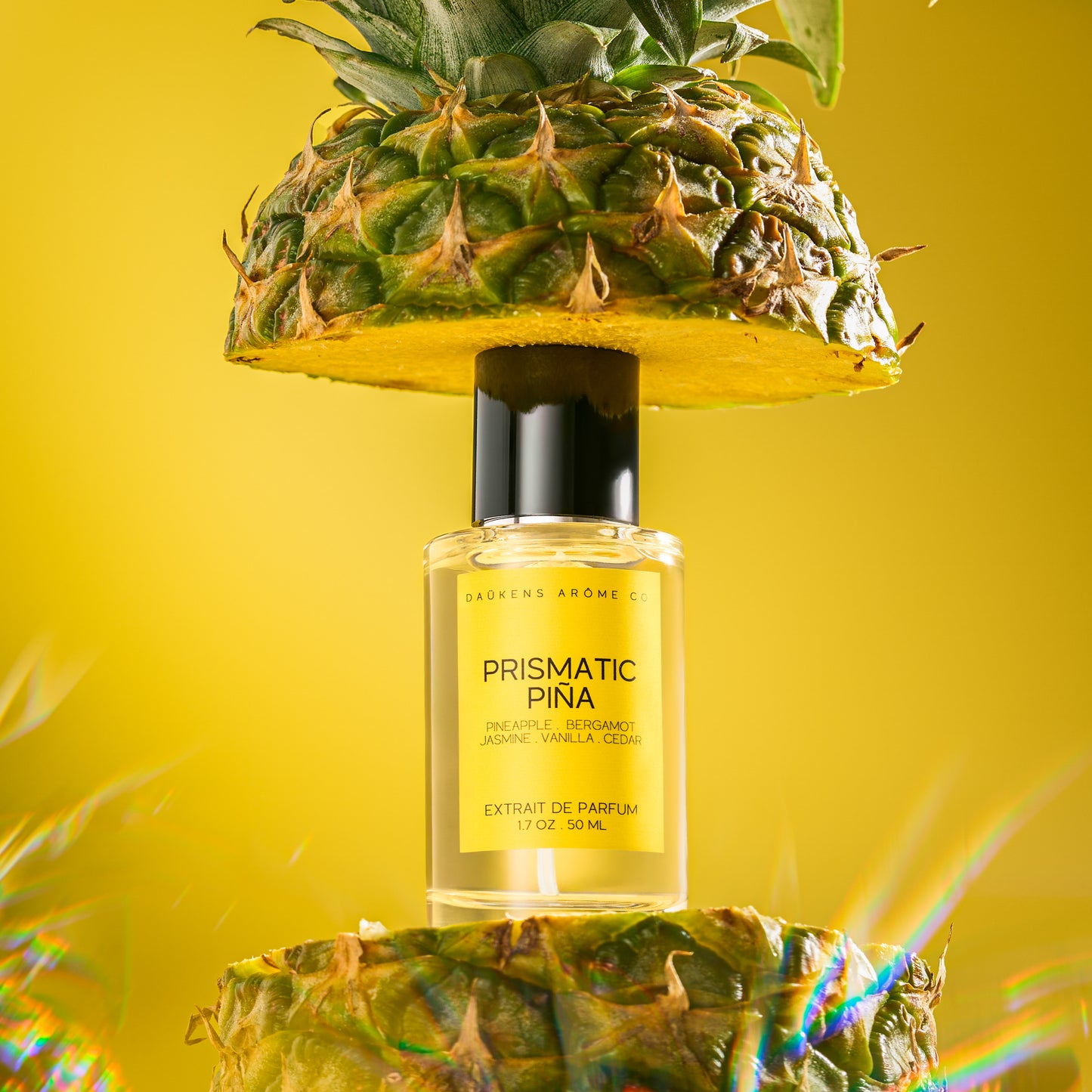 Perfume bottle labeled 'Prismatic Pina' on a yellow background with pineapple elements.