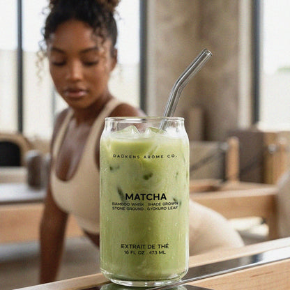 Matcha green tea drink in a glass with a straw, featuring the brand 'DAUKEN'S ARÔME CO.' on a blurred background.