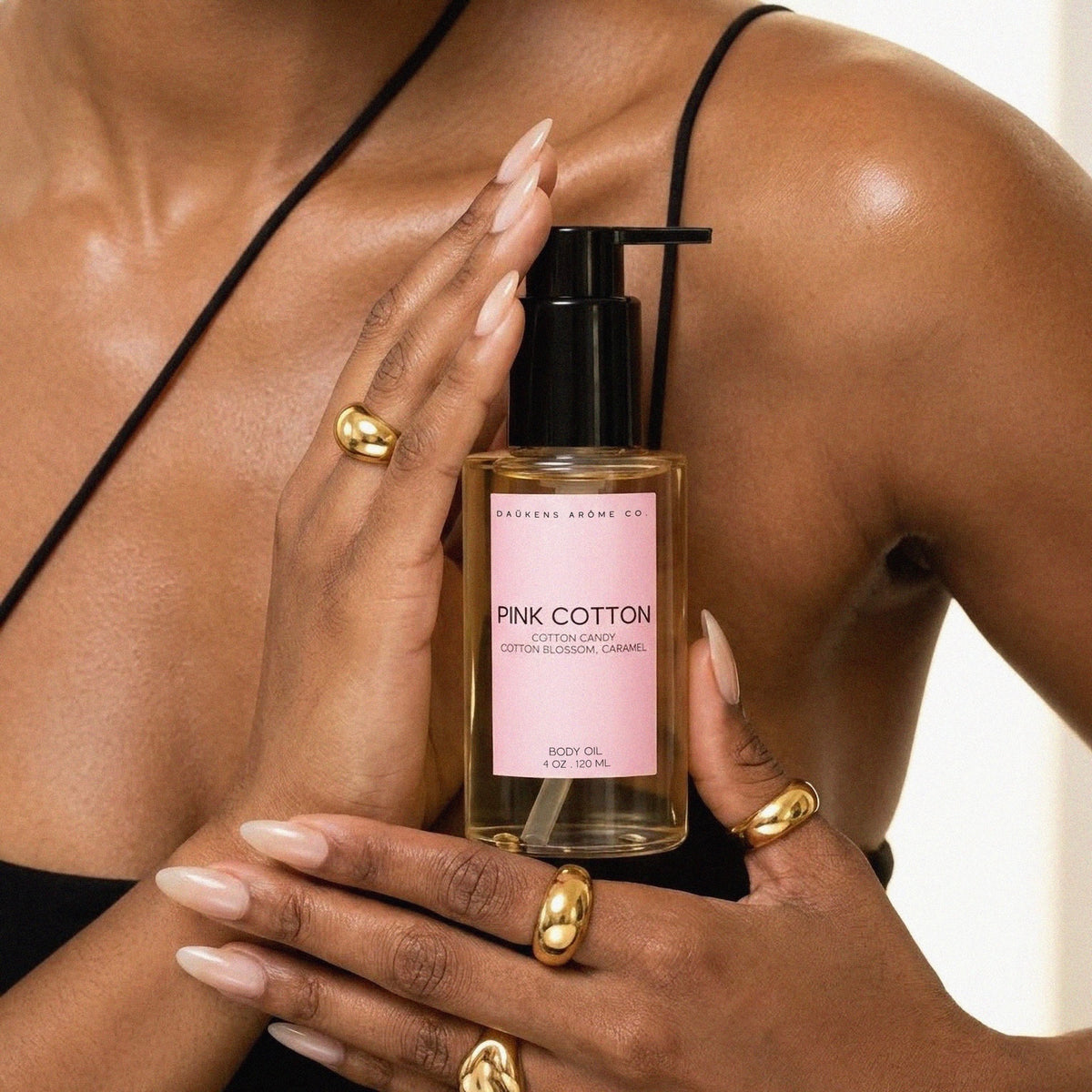 Pink Cotton Body Oil held against a woman's shoulder